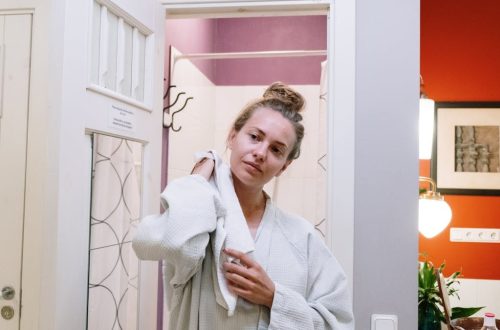 A woman in a bathrobe drying off after a shower in a cozy home bathroom.
