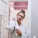 A woman in a bathrobe drying off after a shower in a cozy home bathroom.