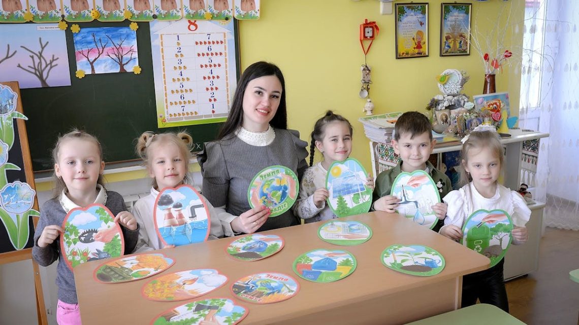 Children and teacher engaging in a classroom activity with art projects.