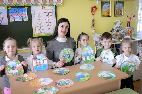 Children and teacher engaging in a classroom activity with art projects.