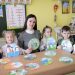 Children and teacher engaging in a classroom activity with art projects.